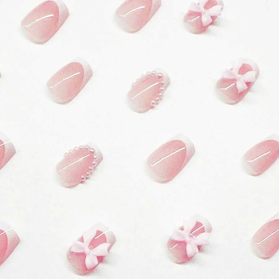 Artificial press-on nails with French manicure style showing bow patterns and tulip designs on short European square nails