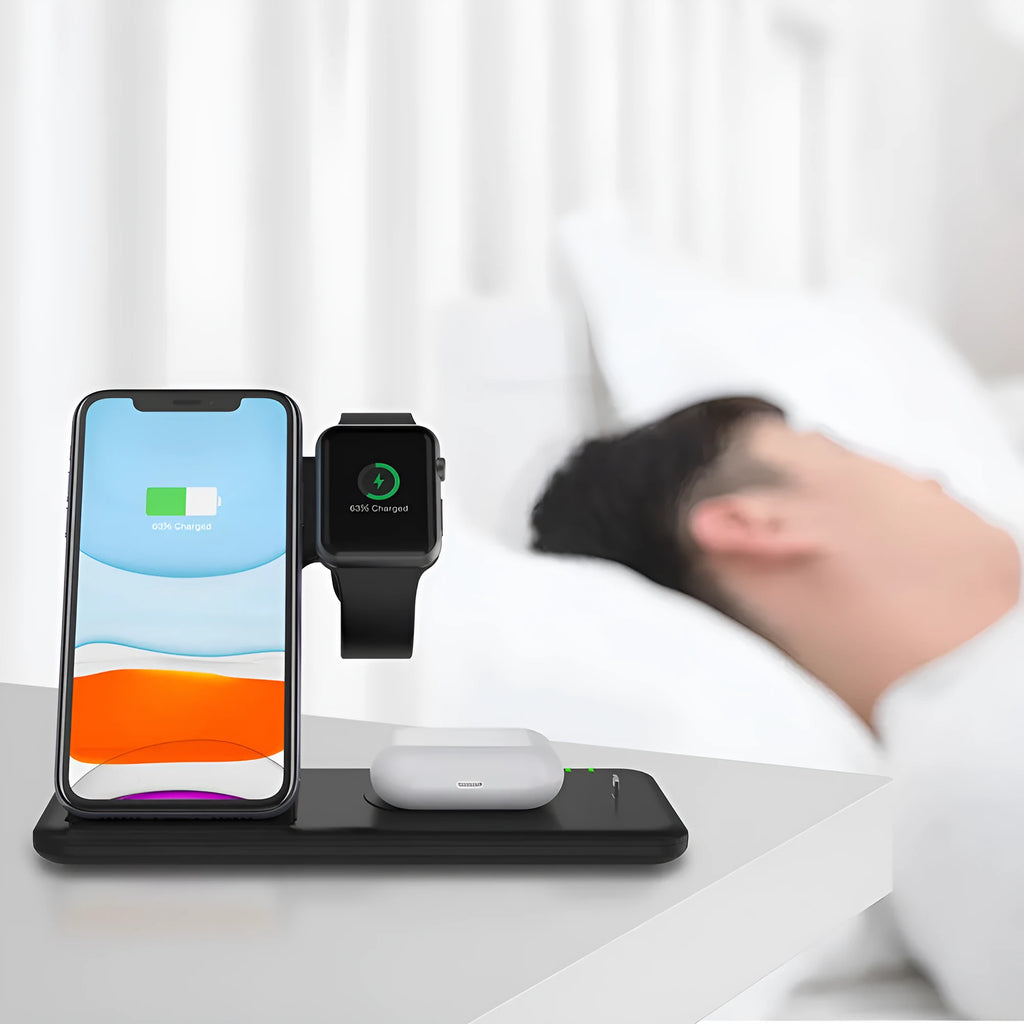 White three-in-one wireless charging stand holding a mobile phone, a smartwatch, and wireless earbuds on a desk.