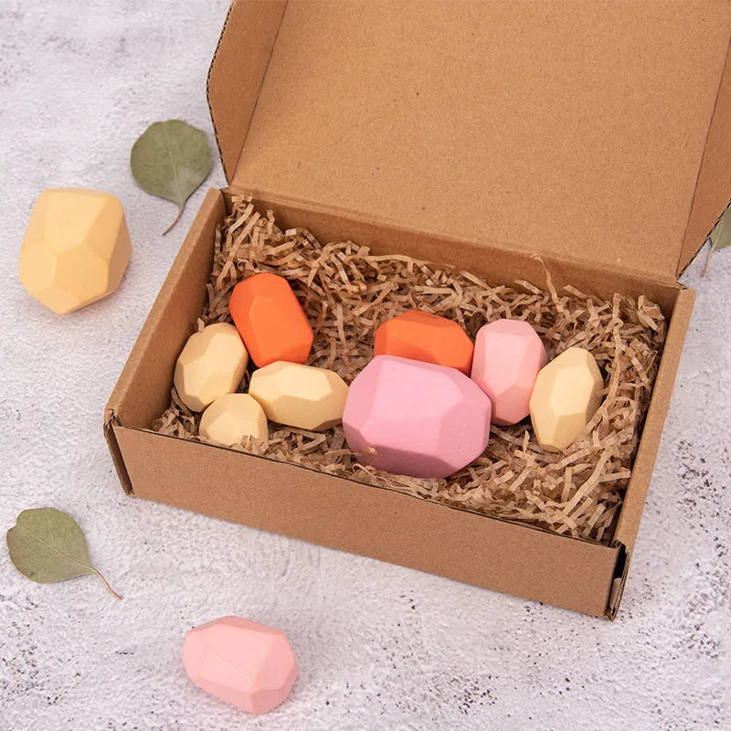 Wooden building block set with coloured and natural stone stacks on a table, suitable for children aged 4-6