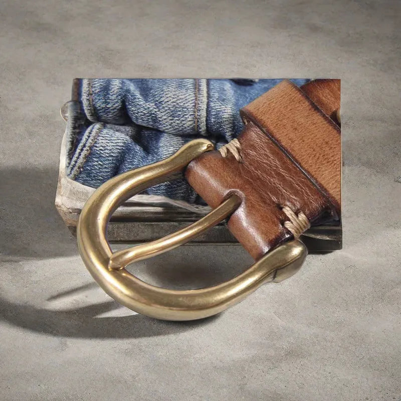 Men's black cattlehide leather jeans belt with a copper pin buckle on a wooden background.