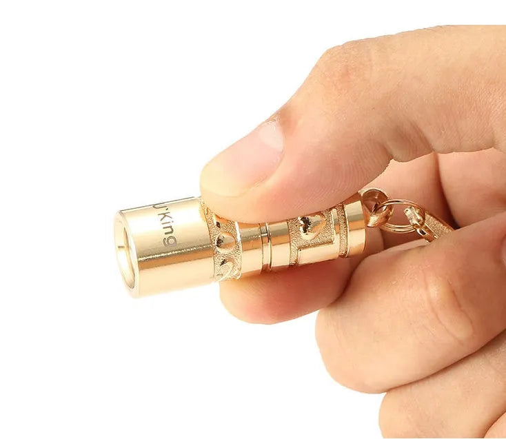 Gold-coloured zinc alloy waterproof mini LED flashlight on a keychain ring.