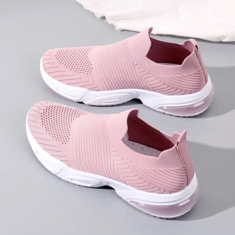 A pair of low-top slip-on sock shoes with a mesh upper and PVC sole on a plain background.