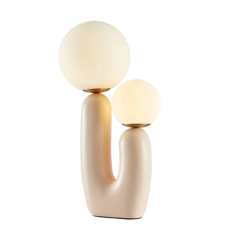 Pink double-head resin table lamp with glass shade on a bedside table, 49cm tall