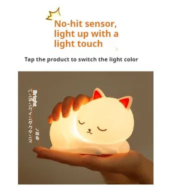 Sleepy cat silicone night light with warm white glow, induction pat feature, on a bedside table