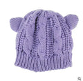 Hand made knitted 3D cat ear beanie in beige on a white background, winter wool hat
