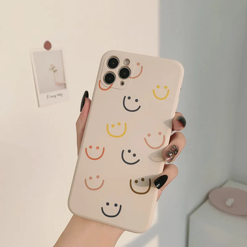 Simple TPU silicone iPhone case with painted smiley face and graffiti design on a table