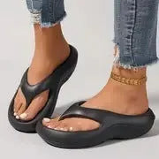 A pair of women's thick-soled flip-flops in grey, showing the EVA material and non-slip footbed texture.