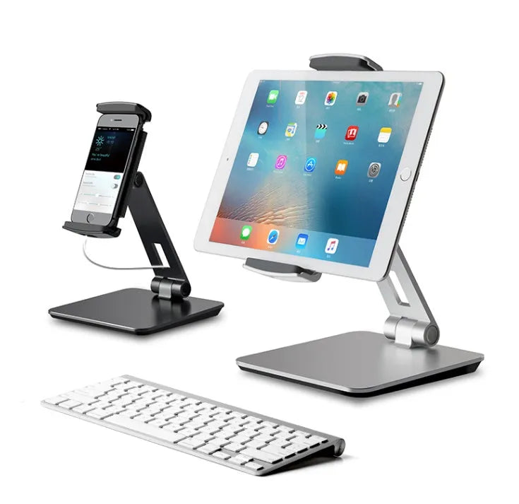 Silver foldable aluminium phone and tablet stand on a desk, holding a tablet at an angle.