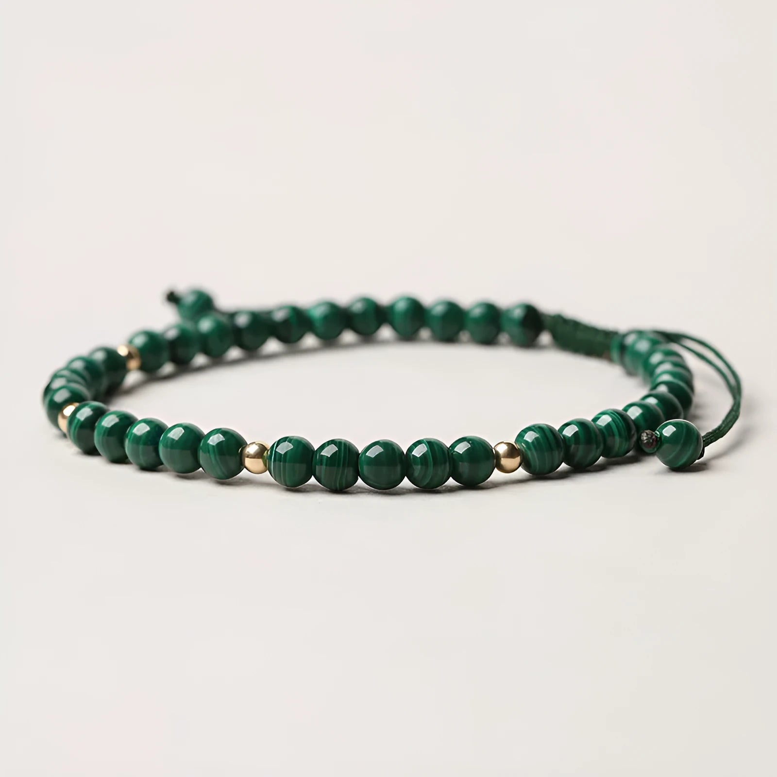Green malachite stone bracelet with golden beads on woven strap, zodiac animal motif.