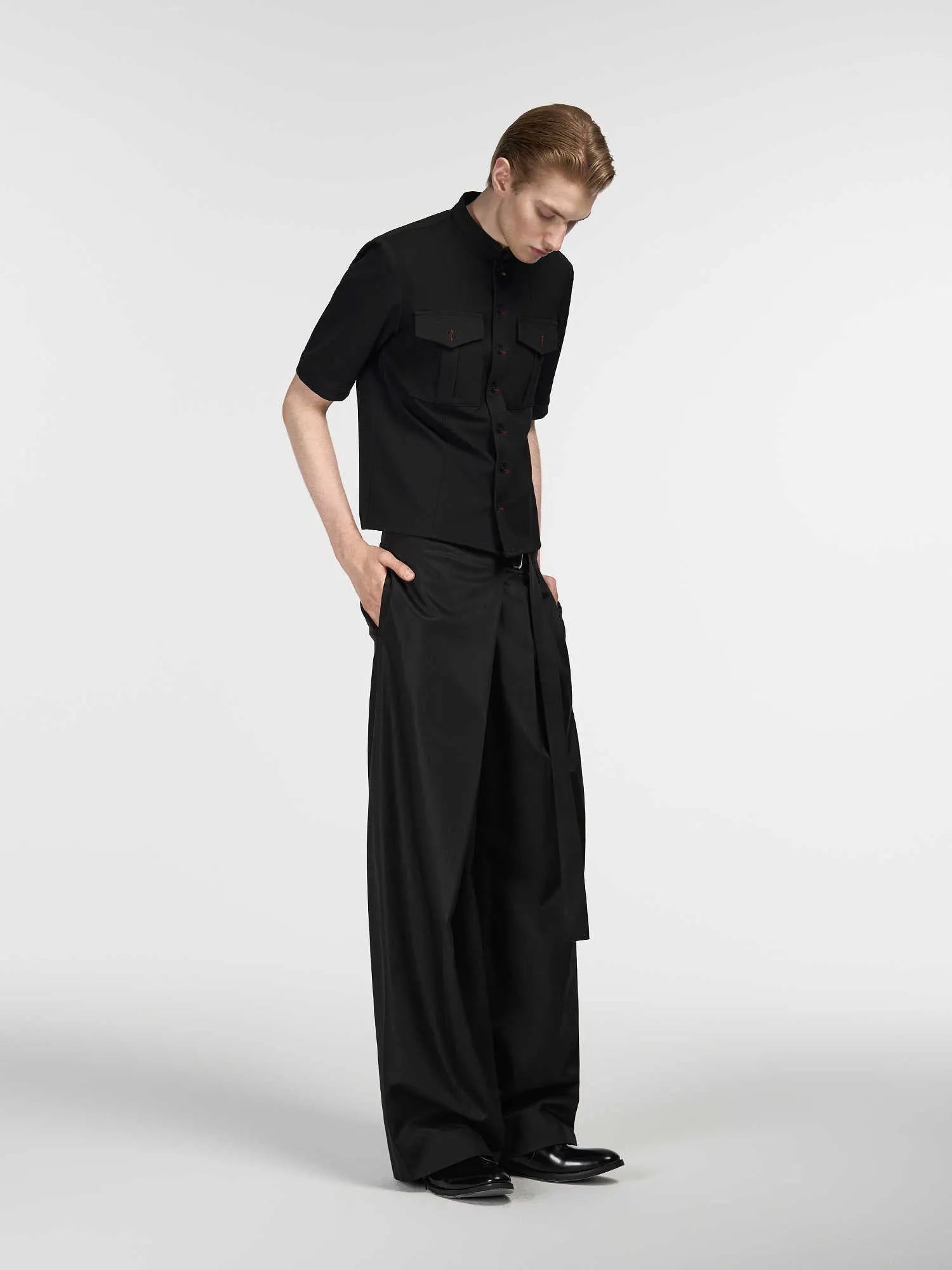 Black single pleated straight-leg trousers with an adjustable waistband on a hanger.