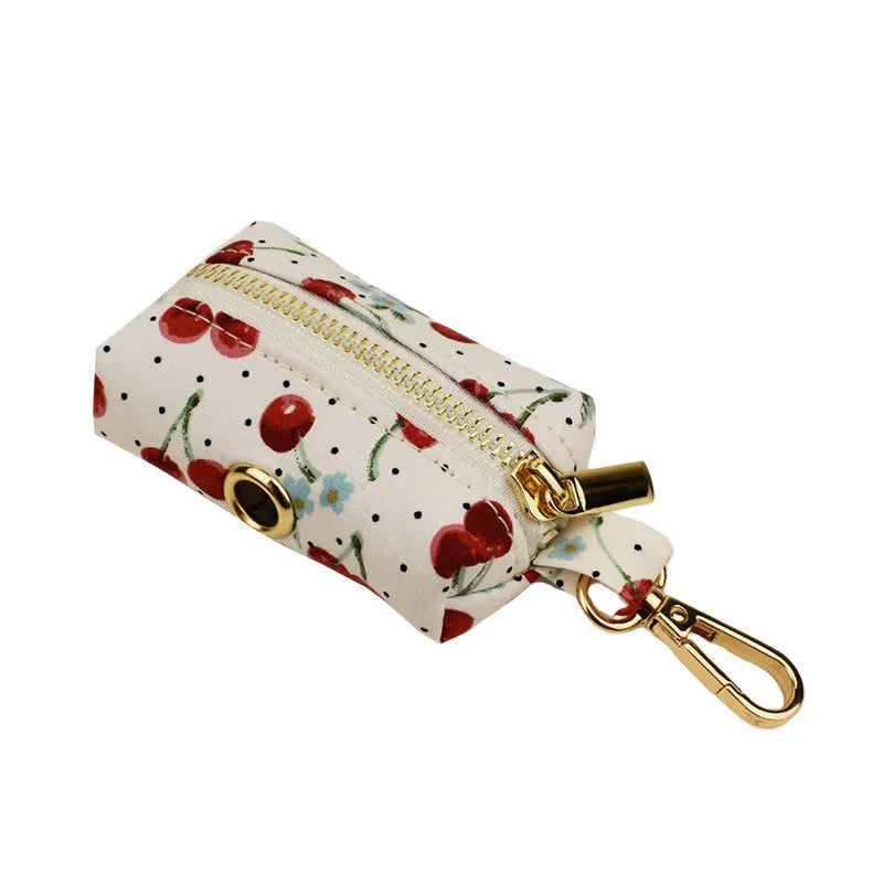Red cherry print dog collar and leash set with light gold buckle, matching vest, bow, and poop bag holder.