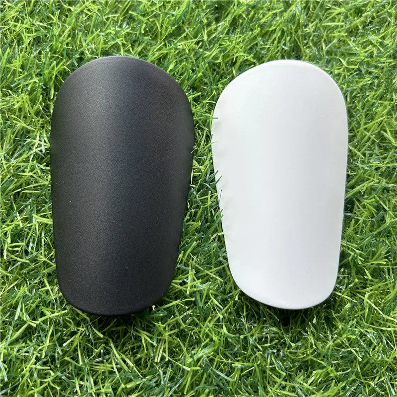Pair of extra small black and white plastic football shin guards, measuring 8cm by 5cm.