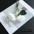 Single artificial mini carnation fake flower in soft rubber and silk material on white background