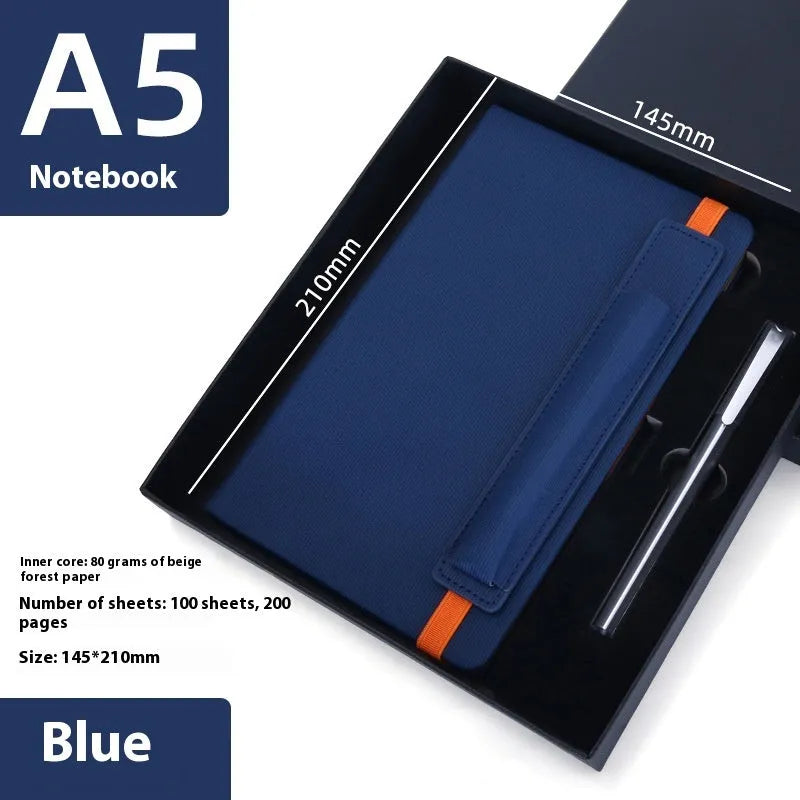 A5 faux leather notebook with pen insert and strap, open on a desk showing lined pages