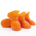 Set of four soft-soled rubber pet rain shoes in assorted colours on a grey background.
