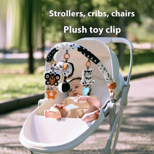 Baby lathe clip hanging plush toy in black and white with pull vibration teether, attached to a cot