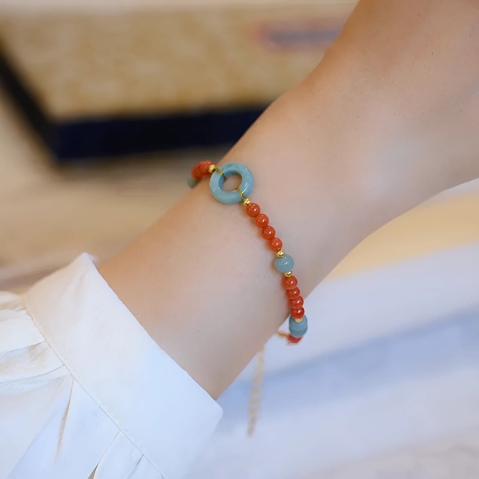 A woman's adjustable South Red Agate bracelet with 4mm beads and a safety buckle on a wrist.