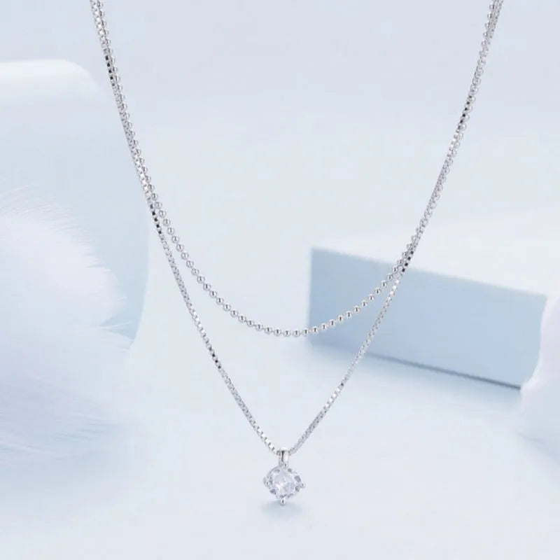 Close-up of a double-layer sterling silver necklace with a pearl-style chain, showing its layered design and silver finish.
