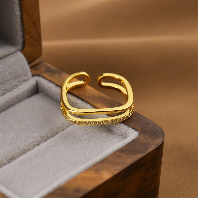 Gold electroplated geometric women's ring with an open adjustable design on a plain background