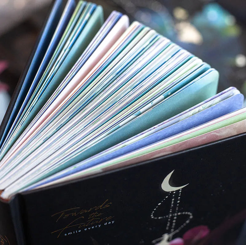 A5 notebook with luminous cover open to show colourful illustration pages, in Deep Blue, Gold, Light Blue, and Purple colour options.