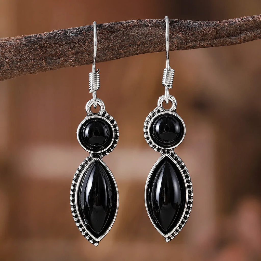 A pair of vintage geometric bohemian pendant earrings in black and purple with round design elements.