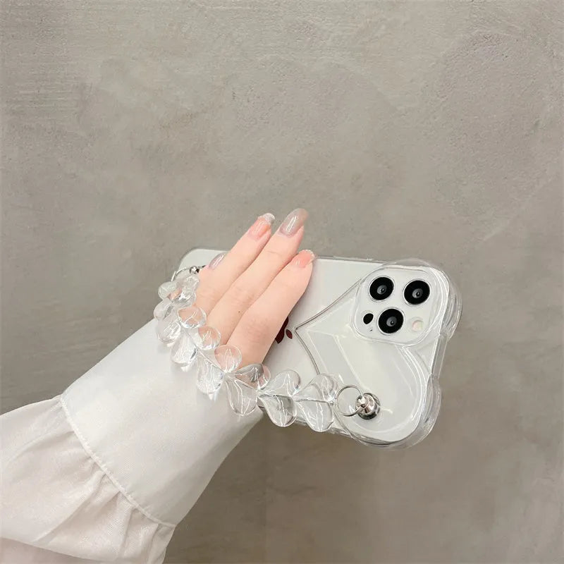 Clear iPhone case with transparent love heart bracelet charm attached, showing soft TPU material.