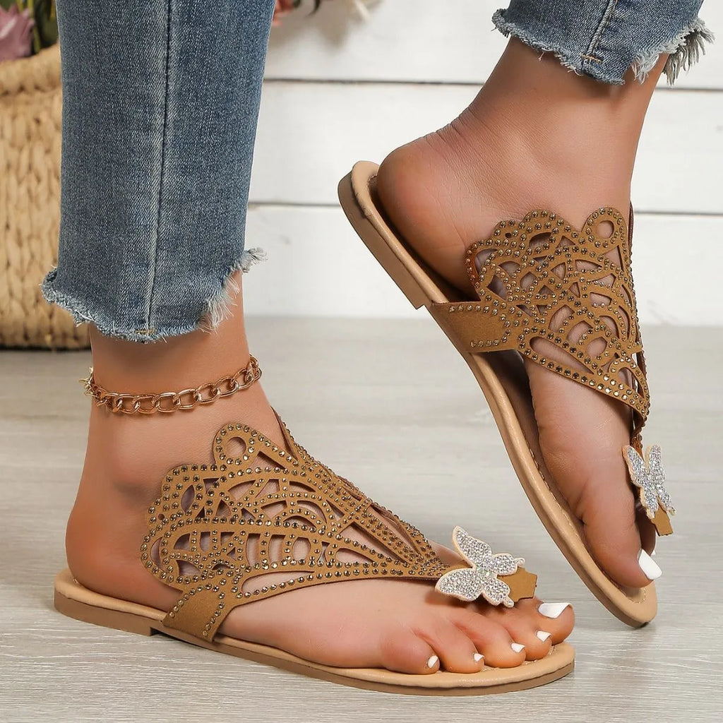 Women's black slip-on sandals with rhinestone details and flip-toe design on a flat rubber sole