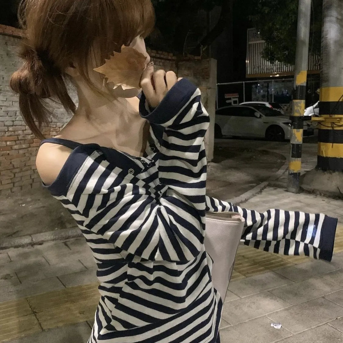 Dark blue oversized women's long-sleeved t-shirt with embroidery, stripes, and button detail on a hanger.