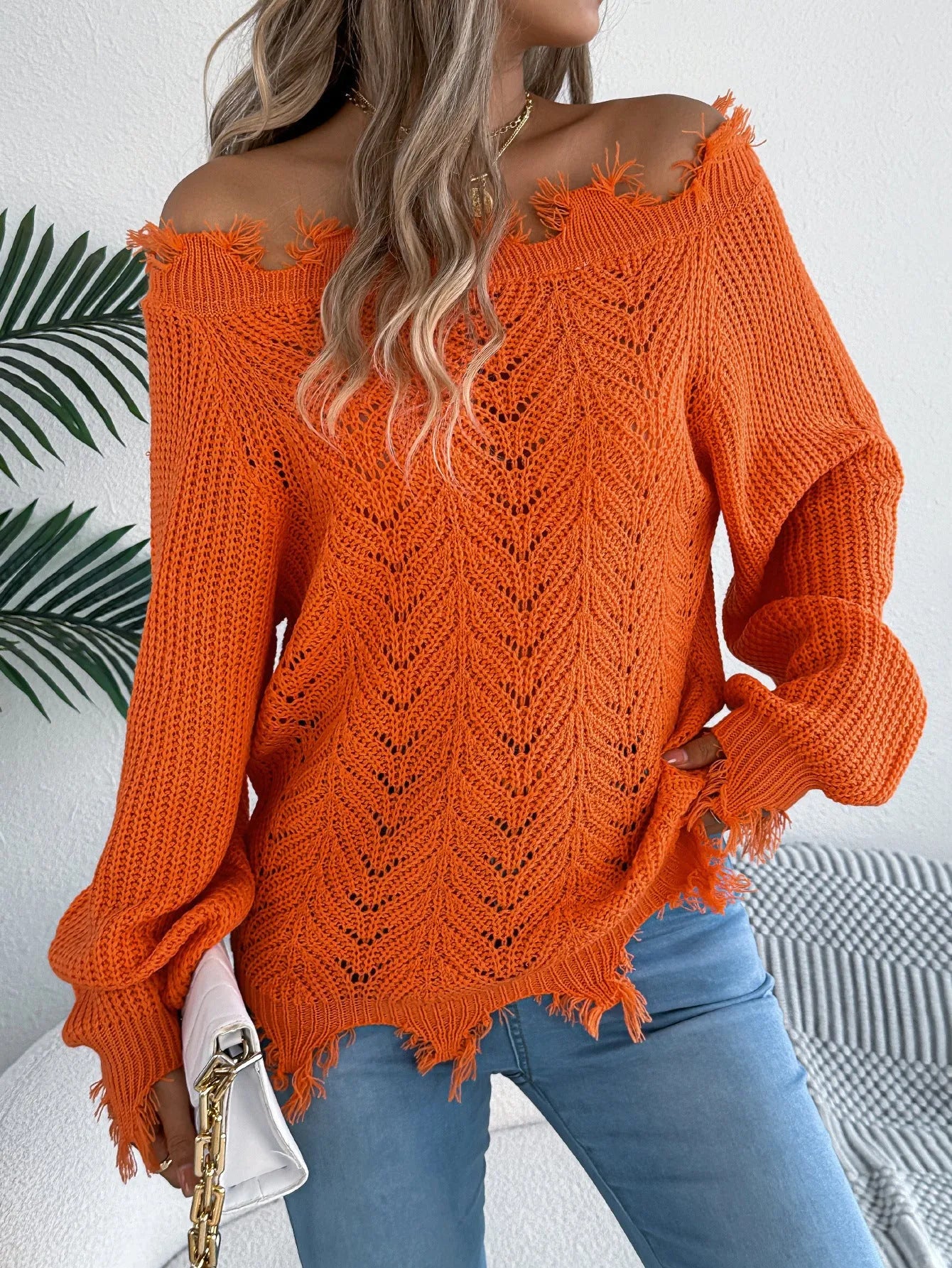 White cut-off-shoulder pullover sweater with hollow-out long sleeves on a mannequin.