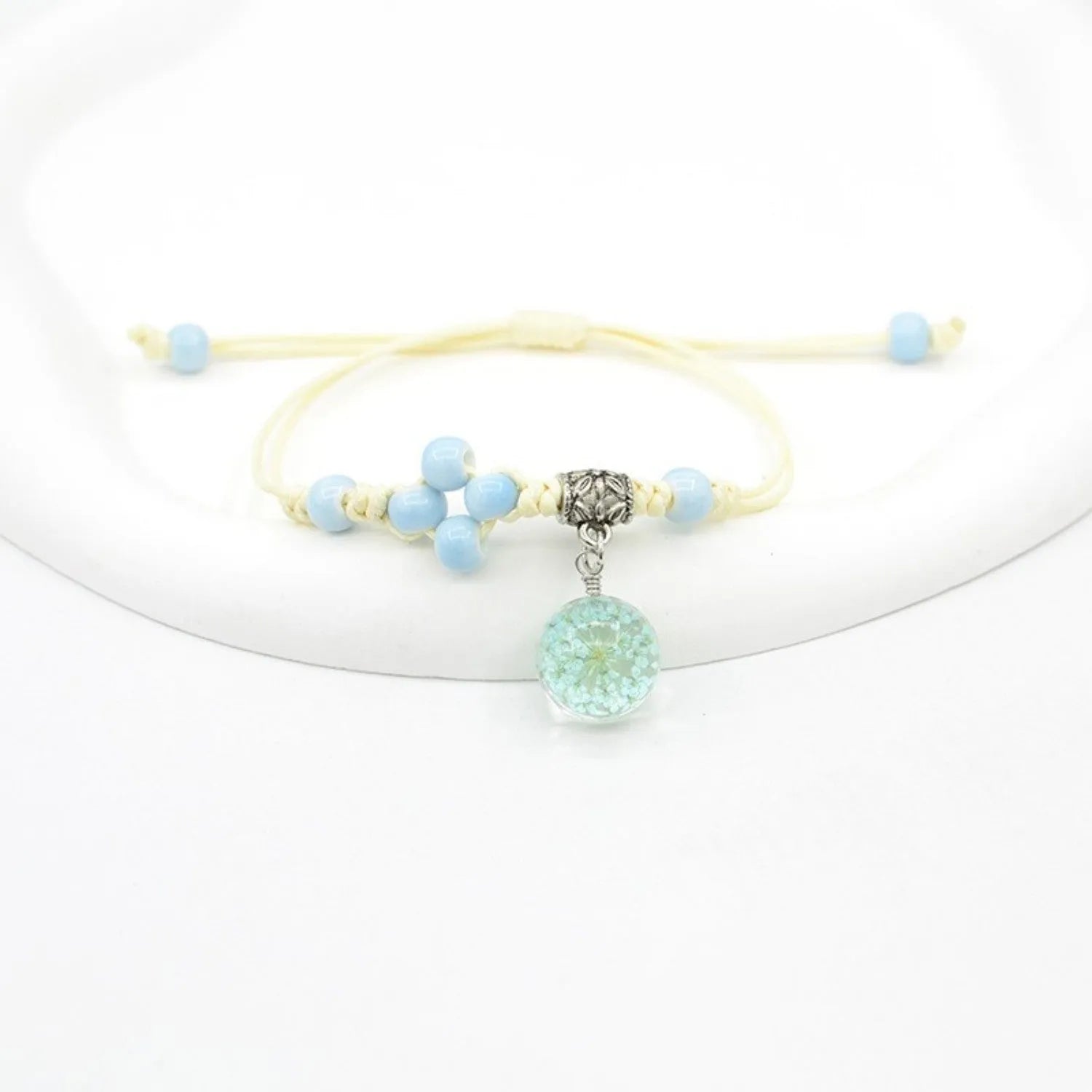 Close-up of a hand-woven glass bracelet with large 1.4cm beads containing real dried flowers in various colours.