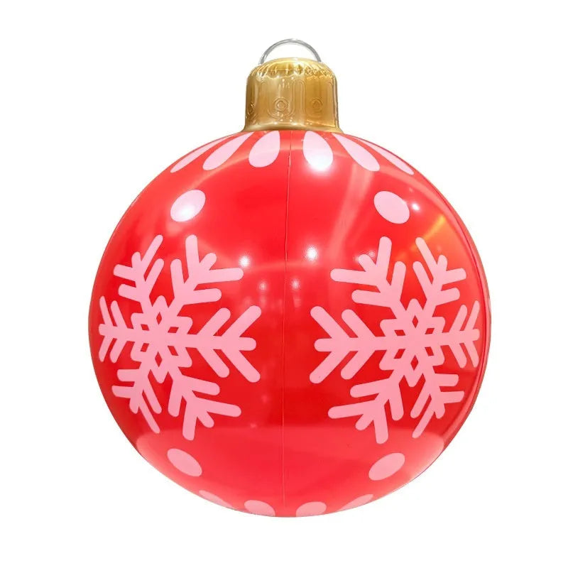 Large red inflatable Christmas ball with flashing lights displayed on a winter garden lawn.