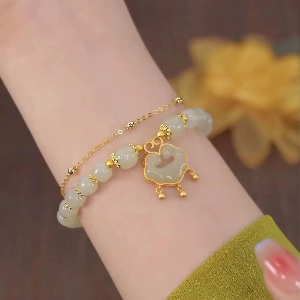 Close-up of a women's green double-layer bracelet with a drop-shaped Xiangyun safety lock pendant.