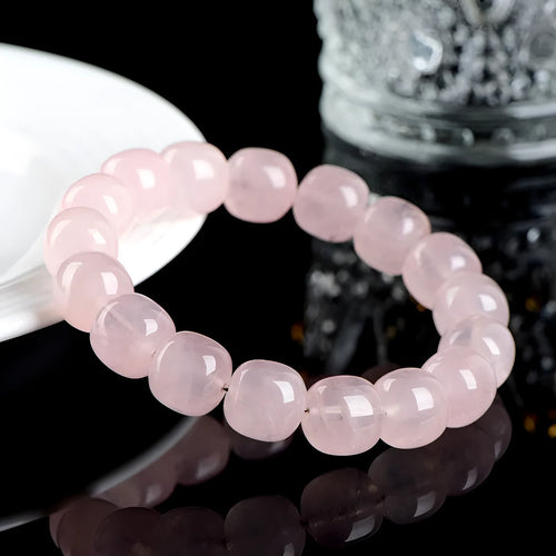 Close-up of a pink geometric bracelet with barrel-shaped crystal beads on a wrist.