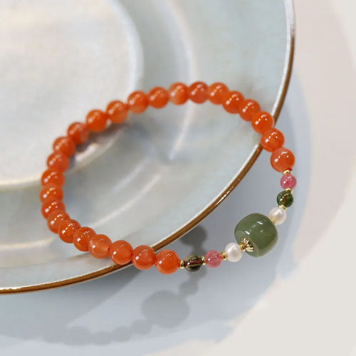 Women's bracelet made of round red South agate beads from Sichuan on a black elastic cord.