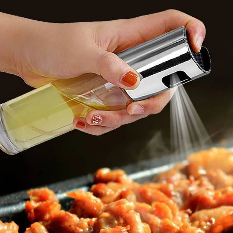 Gold pump-action oil and vinegar spray bottle with 100ml glass body on kitchen counter.