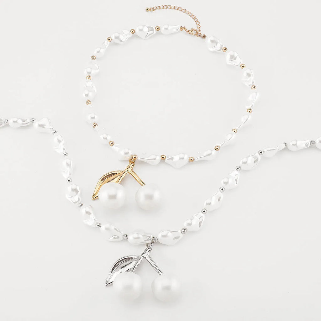Gold fruit and geometric pendant necklace on a pearl chain, adjustable 51-60cm length.