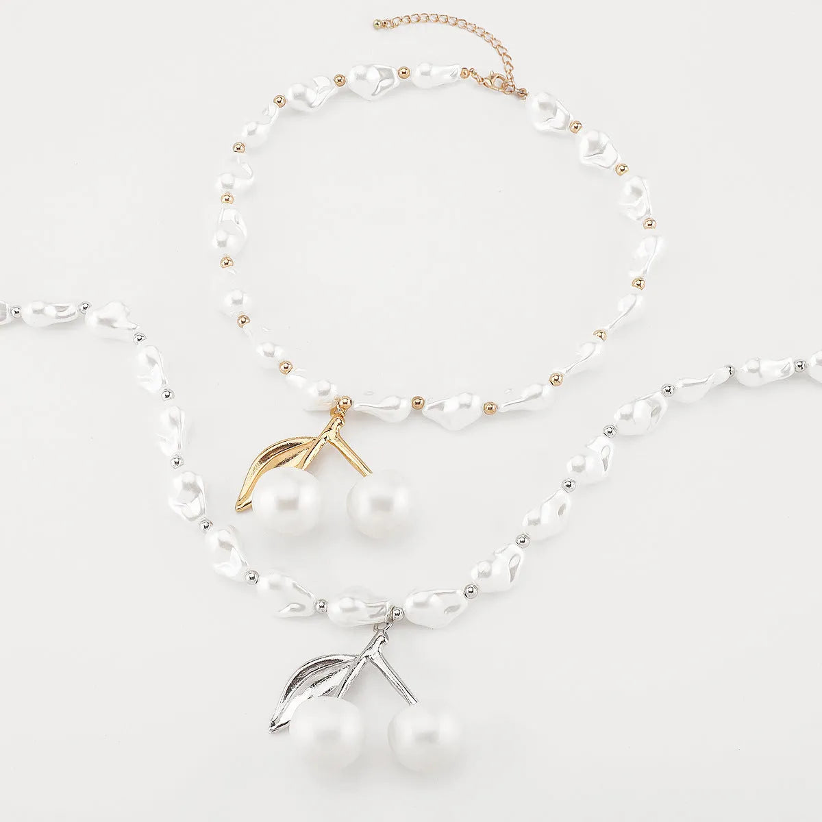 Gold fruit and geometric pendant necklace on a pearl chain, adjustable 51-60cm length.