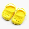 A pair of small plastic doll beach slippers in blue, red, yellow, or green colours.