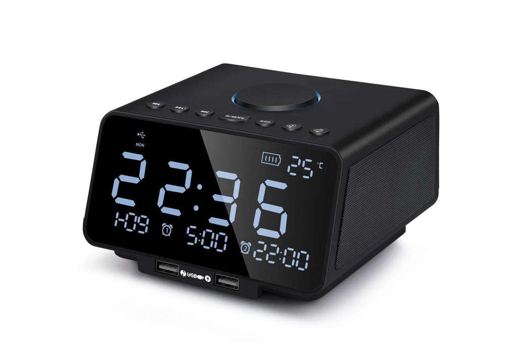 Black and white wireless alarm clock speaker with Bluetooth, radio, and USB playback functions on a bedside table.