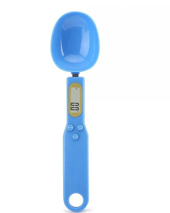 White digital kitchen scale with LCD screen displaying weight, shown next to a measuring spoon.