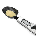 Black digital measuring spoon with LCD display showing weight measurement for kitchen use