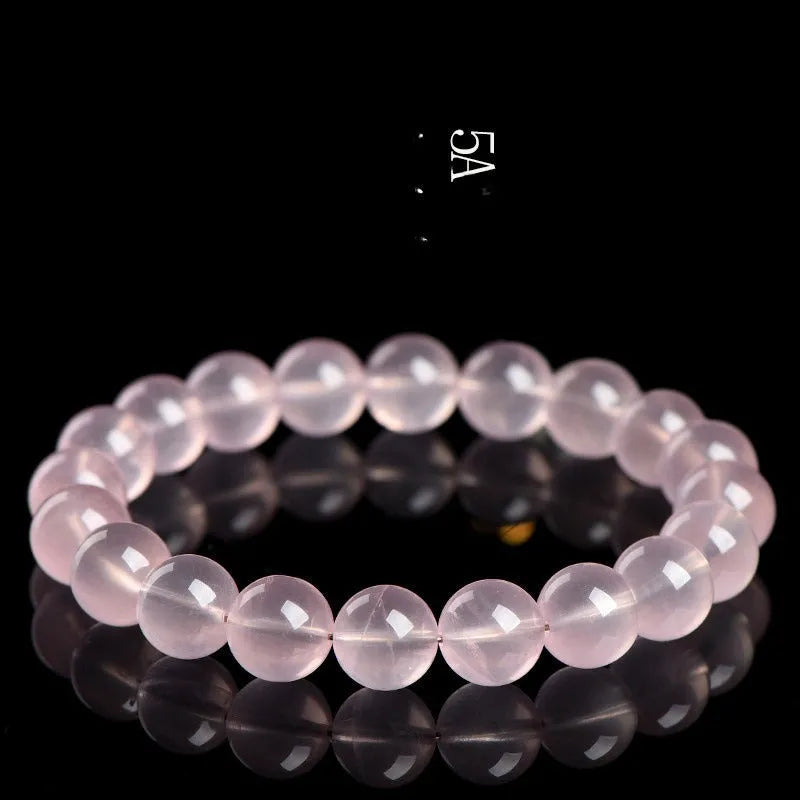 A polished natural starlight crystal round bead bracelet in pink, shown in a single circle design.