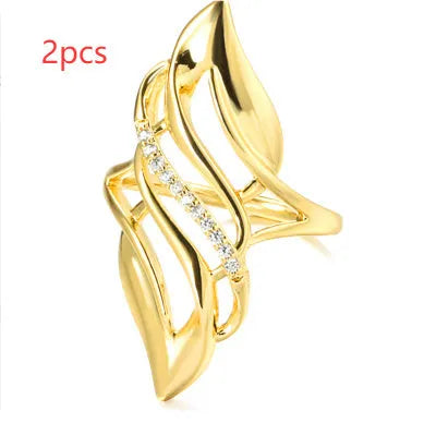Gold tone women's ring with an exaggerated curved design on a model's finger.