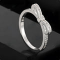 Silver electroplated bow ring with sparkling zircon crystals on a finger.