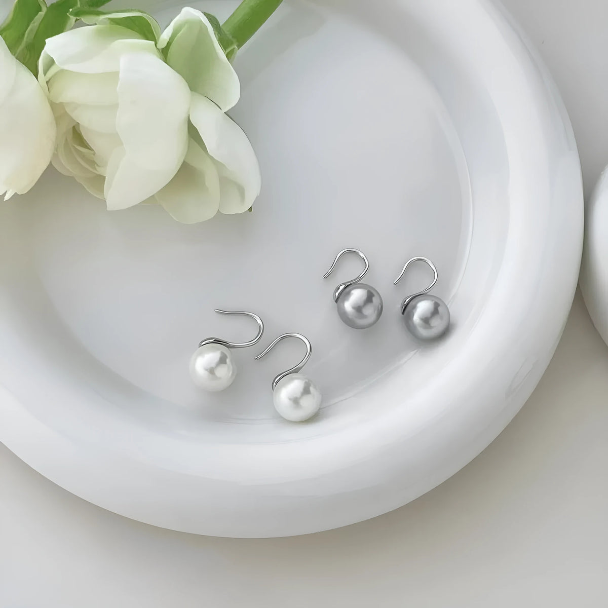 Silver round stud earrings with 12mm white shell pearl inlay on simple background