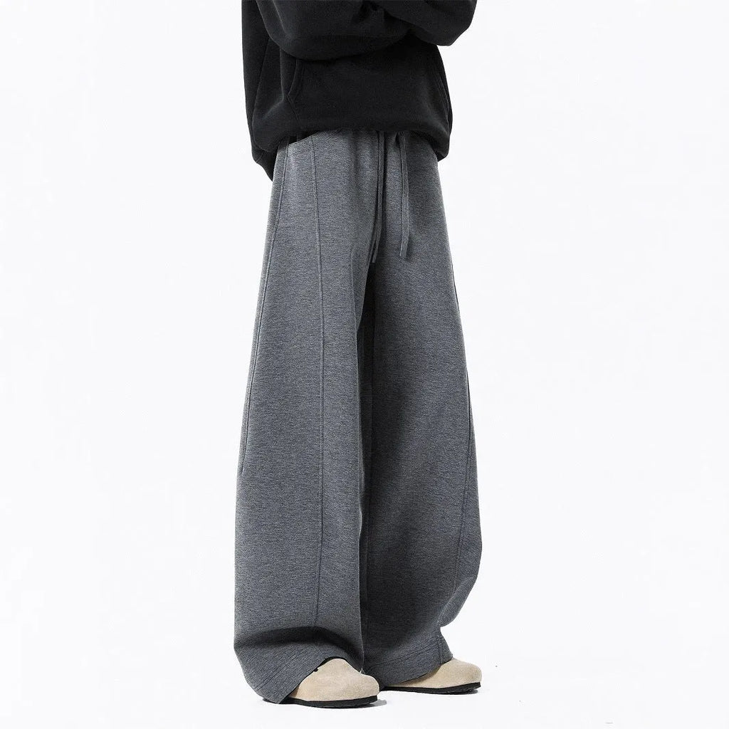 Men’s relaxed fit dark gray trousers with drawstring waist and belt on model