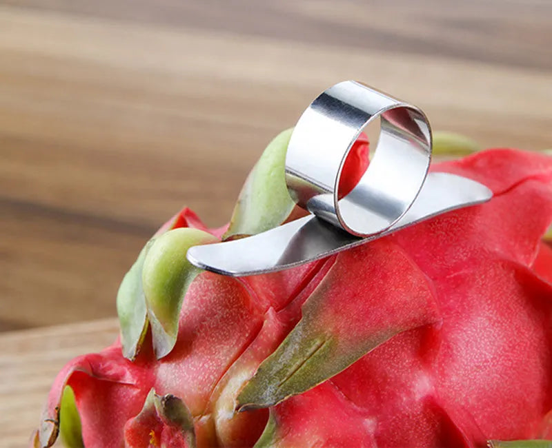 Silver stainless steel citrus fruit peeler with a ring-shaped handle on a kitchen surface.