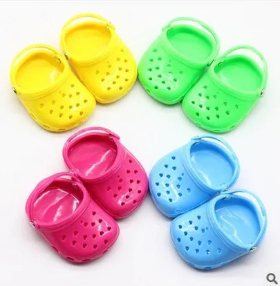 A pair of small plastic doll beach slippers in blue, red, yellow, or green colours.