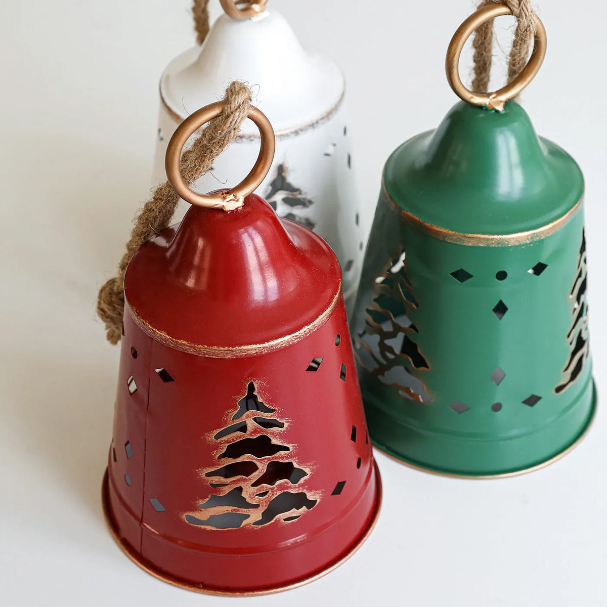 Wrought iron Christmas bell ornament in red, green, and white with hanging loop on a white background