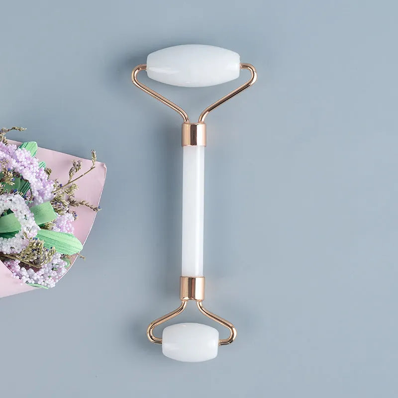 White jade facial roller and gua sha tool set with rose quartz board on a neutral background.